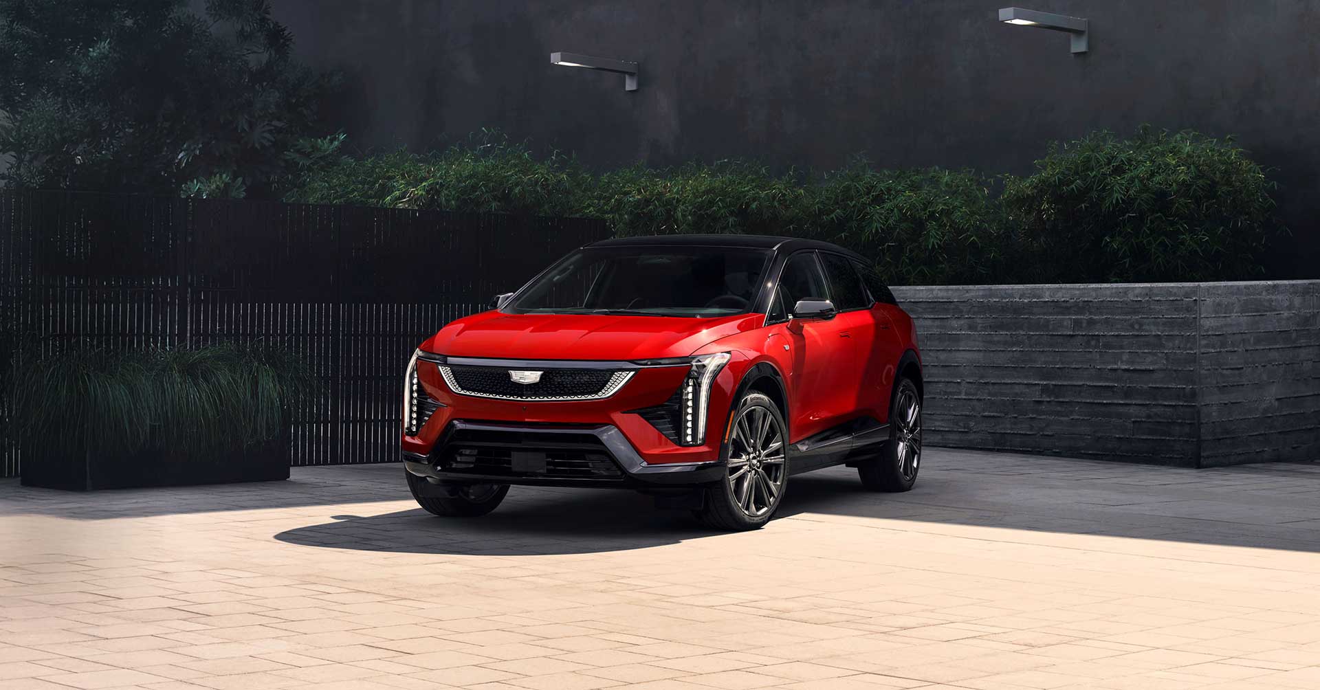Red Cadillac Optiq electric SUV parked outside a modern building