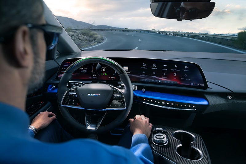 Front View of the 2026 OPTIQ-V Driving Through the Dusk Utilizing its Headlights | Arnie Bauer Cadillac in Matteson IL