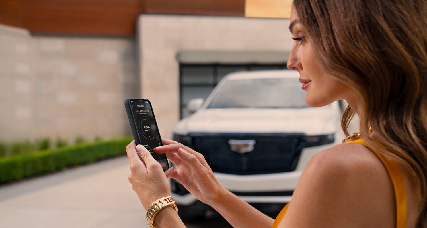 lady checking her mobile with a Cadillac vehicle background | Arnie Bauer Cadillac in Matteson IL